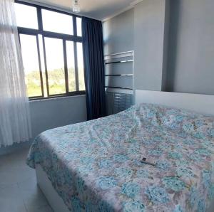 a bedroom with a bed with a floral bedspread and a window at Apartament M&L in Golem