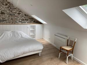 a attic bedroom with a bed and a chair at Au Graé - Maison à louer à Laruns Béarn in Laruns