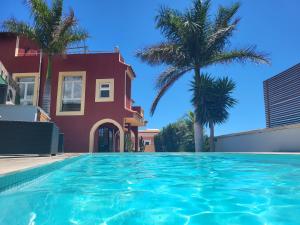 a swimming pool in front of a house with palm trees at Casa Viera in Buzanada