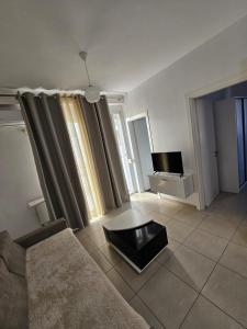 Una sala de estar con un sofá y un televisor en Redsun Apartment, en Vlorë