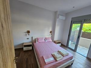 a bedroom with a bed with pink sheets and a window at Cute Corner in Khalkoútsion