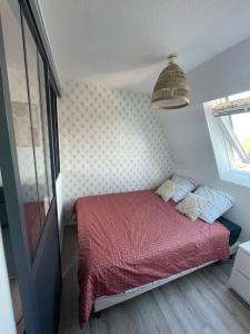 Un pequeño dormitorio con una cama con una manta roja. en Studio Vue Mer, en Villers-sur-Mer