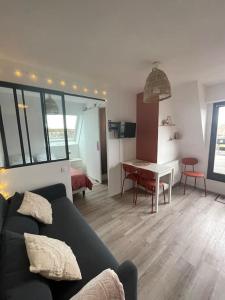 Una sala de estar con un sofá negro y una mesa. en Studio Vue Mer, en Villers-sur-Mer