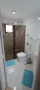 ein Badezimmer mit Toilette und Dusche mit blauen Matten in der Unterkunft Apartamento em Enseada - Guarujá in Guarujá