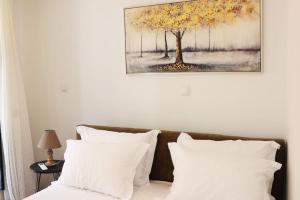 a bed with white pillows and a painting on the wall at Titinas' in Plomari