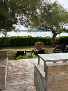 eine Holzterrasse mit einem Tisch, Stühlen und einem Baum in der Unterkunft Hotel Thalassa in Cargèse