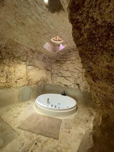 a bath tub in a cave with a stone wall at Amarcord private Spa Ostuni in Ostuni