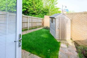 a backyard with a fence and a wooden shed at Cosy 5 Bedroom House With Parking in Chatham