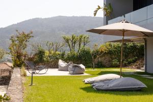 eine Terrasse mit Sonnenschirm und Kissen auf dem Rasen in der Unterkunft Just Like Home - Casal no Campo in Vila Praia de Âncora