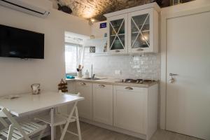 eine Küche mit weißen Schränken und einem Tisch in der Unterkunft KAMBUSA LOFT - Mono fronte mare in Santo Stefano al Mare
