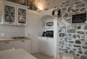 a kitchen with white cabinets and a stone wall at KAMBUSA - Mono Fronte Mare in Santo Stefano al Mare