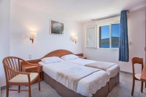 - une chambre avec un lit, une chaise et une fenêtre dans l'établissement Le Neptune & Spa, à Propriano