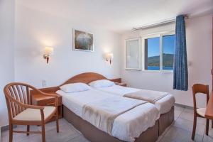 a bedroom with a bed and a chair and a window at Le Neptune & Spa in Propriano