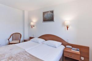 a hotel room with a bed and a chair at Le Neptune & Spa in Propriano