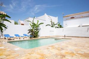 a swimming pool with blue chairs and a building at La Floristería Zahora in Zahora +20 photos