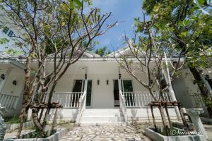 a white house with trees in front of it at Bananaleaf Wedding Cafe & Resort in Ban Bang Kaeo