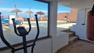 a gym with a view of a swimming pool at Villa avec piscine Asilah, terrain de foot privative in Asilah