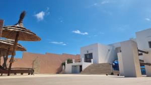 a building with a straw umbrella next to a staircase at Villa avec piscine Asilah, terrain de foot privative in Asilah
