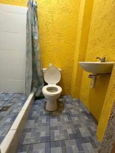 a yellow bathroom with a toilet and a sink at Yaxlik River Lodge in Lanquín