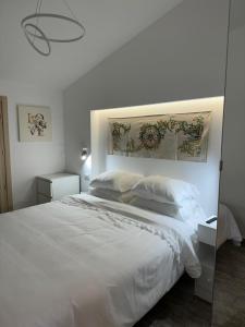 um quarto branco com uma cama grande com lençóis e almofadas brancos em Attico Mare Taormina with parking em Taormina