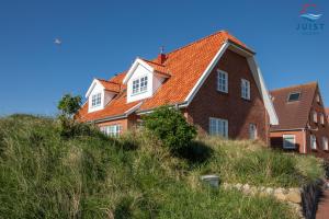ein Haus mit einem orangenen Dach auf einem Hügel in der Unterkunft Haus Seepferdchen 238 - Ferienhaus Watt in Juist