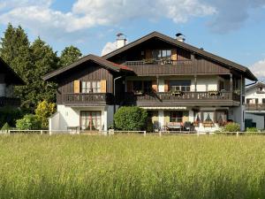 a large wooden house with a field in front of it at Ferienwohnung Alpina 1 in Wallgau
