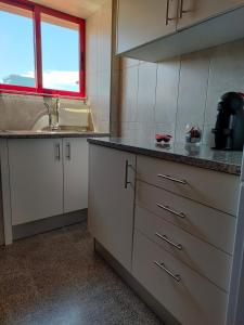 uma cozinha com armários brancos, uma pia e uma janela em Apartamento Boavista em Vila Nova de Gaia