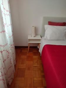 um quarto com uma cama com um cobertor vermelho e uma mesa em Apartamento Boavista em Vila Nova de Gaia