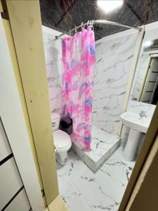 a bathroom with a pink shower curtain and a toilet at Hotel GOLDEN DEGREZ in Bukhara