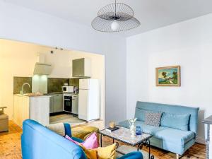 a living room with two blue couches and a kitchen at T3 Familial Pro Tarbes centre in Tarbes