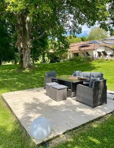 a patio with two wicker chairs and a table at Le Manoir aux Volets Verts with Hot Tub in Salerm