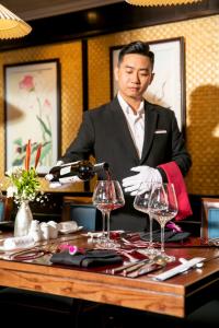 a man pouring a glass of wine at a table at Bhaya Legend Cruises in Ha Long