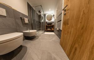 uma casa de banho com um WC branco e um lavatório. em Hotel Gruber em Sesto