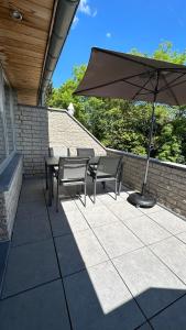 a patio with tables and chairs and an umbrella at Les Terrasses de Malmedy - duplex 430 in Malmedy