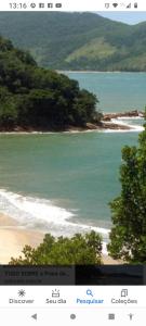 ein Bild eines Strandes mit Bäumen und dem Meer in der Unterkunft casa da Dora próx da praia in Caraguatatuba
