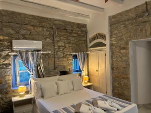 a bedroom with a bed and a stone wall at Thomas Villas on the beach Katapola in Katapola