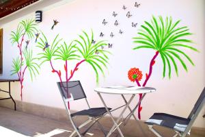 a table and chairs in front of a wall with a palm tree mural at Meraki Ortigia in Syracuse