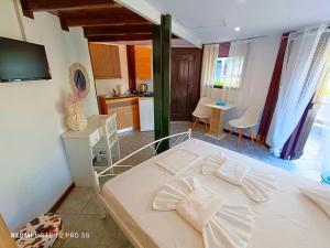 a bedroom with a white bed and a kitchen at Spasmata Village - Marios Bungalows Only Adults 2 min From The Beach in Minia
