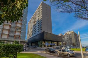 a tall building with cars parked in a parking lot at Excelente! Vista al mar con cochera y amenities gimnasio, play room y pileta no climatizada in Mar del Plata