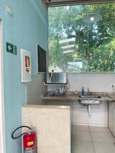 a bathroom with a sink and a window and a fire extinguisher at Pousada PÍER 22 in Caraguatatuba
