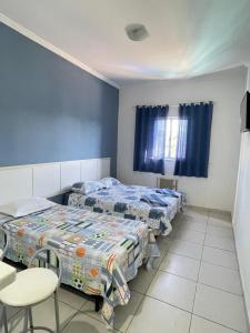 a bedroom with two beds and a table and chairs at Pousada PÍER 22 in Caraguatatuba