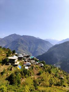 a village on a hill with mountains in the background at Pin Parvati Wooden Cottages - Hidden Monkey Experiences in Sainj