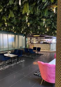 een lobby met tafels, stoelen en planten aan het plafond bij Super Stay Hotel, Oslo in Oslo