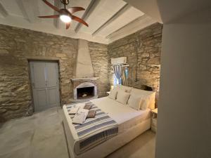 ein Schlafzimmer mit einem Bett und einer Steinmauer in der Unterkunft Thomas Villas on the beach Katapola in Katápola
