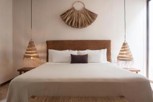 a bedroom with a white bed with two pendant lights at Hotel Casa Hormiga in Bacalar