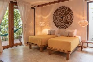 two beds in a room with a window at Hotel Casa Hormiga in Bacalar