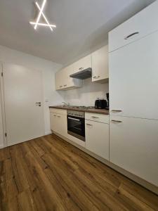 a kitchen with white cabinets and a wooden floor at Luna Apartment in Dinkelsbühl