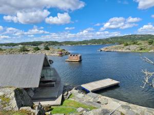 a house on a river with a boat in the water at Usjenert idyllisk Sjøbu in Kragerø