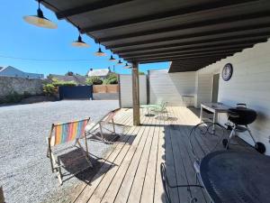 un patio con sillas, una mesa y una parrilla en Appartement moderne avec terrasse - proche mer en Agon Coutainville