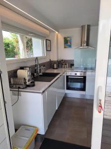 a kitchen with white cabinets and a sink and a window at Appartement moderne avec terrasse - proche mer in Agon Coutainville